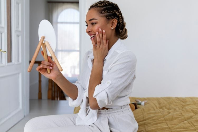 Close-up of a woman applying a gentle facial scrub or chemical exfoliant to smooth and brighten skin texture for part of 10 ways to care for your skin.