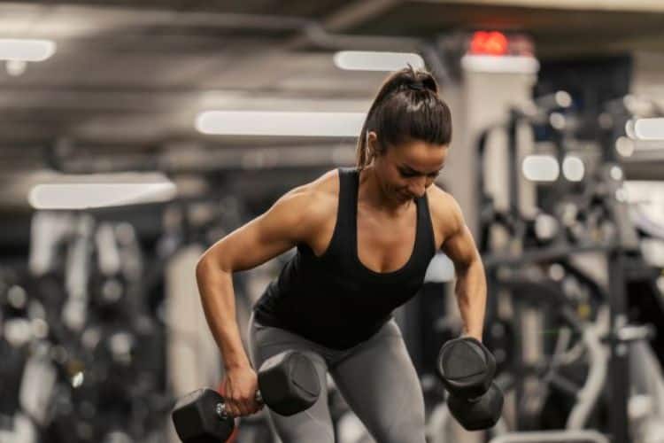 Woman performing dumbbell squat to press during 45 minute full body workout