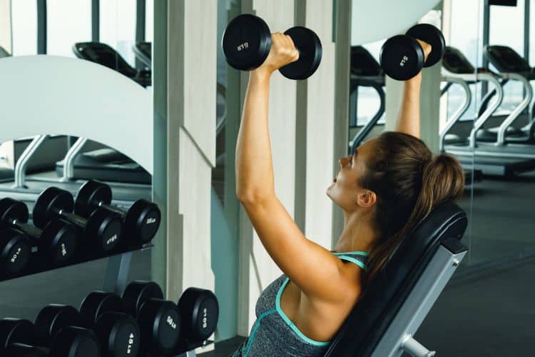 Woman performing overhead press during 45-minute full body strength workout