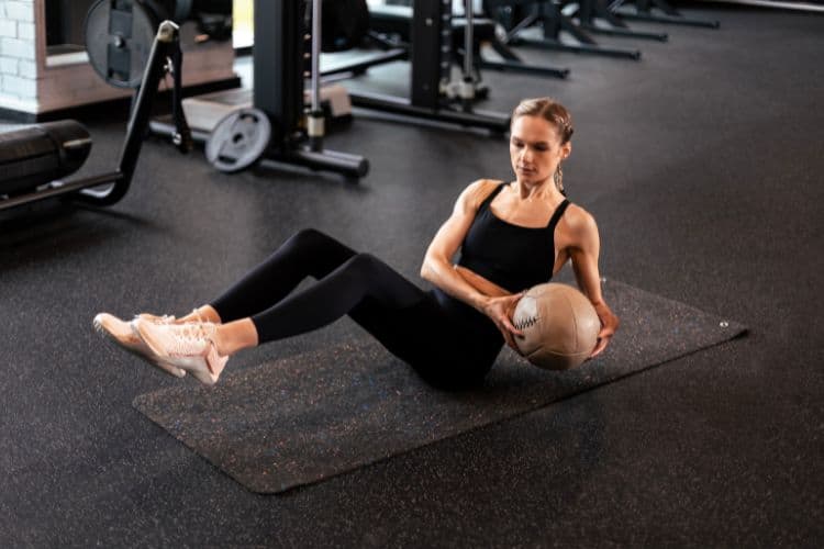 Woman performing Russian twists ab exercises with dumbbell weights for core strength