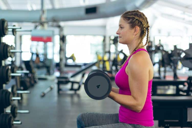 Woman doing dumbbell bicep curls during 30 minute arm workout