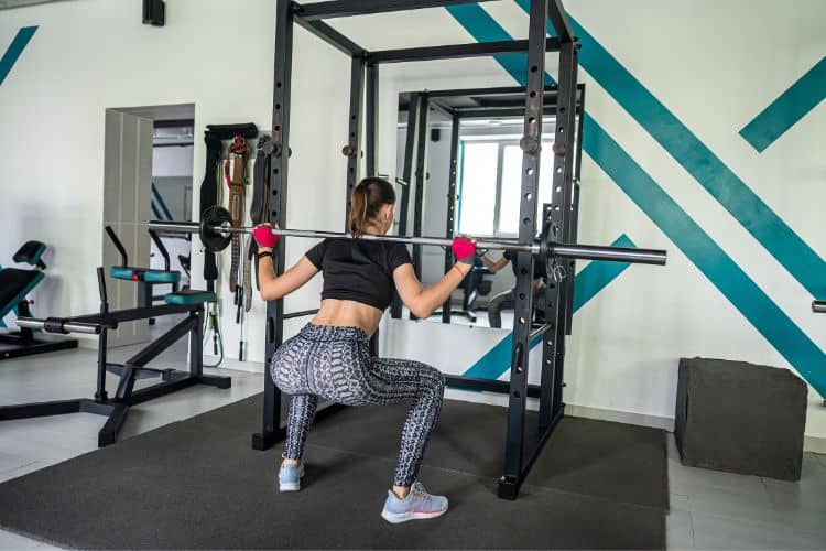 Beginner performing barbell back squat in gym for 30-minute workout