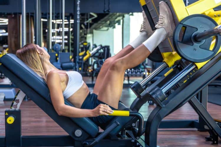 Woman using leg press machine for beginner leg workout routine at the gym