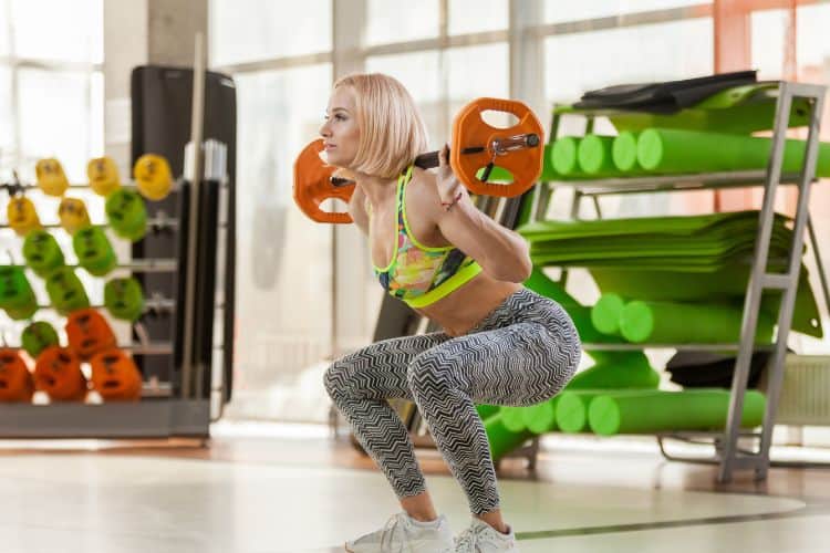 Woman performing barbell squats during a 45-minute lower body workout at the gym