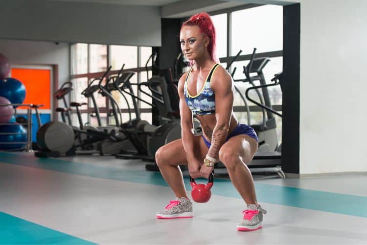 Woman performing barbell back squat during 5-day workout split lower body day