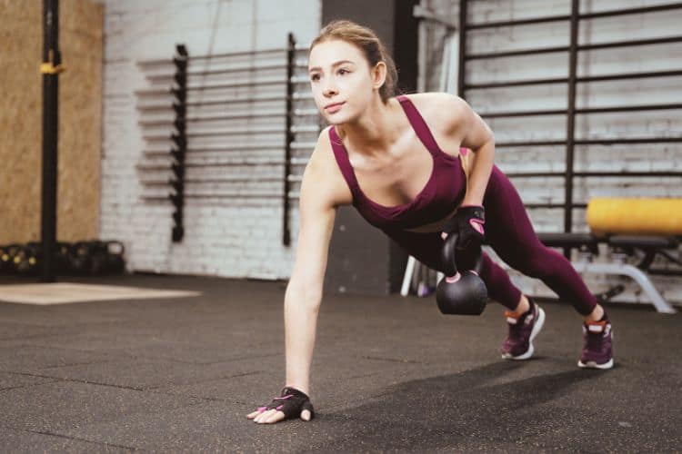 Woman performing a weighted burpee with kettlebells during a circuit workout