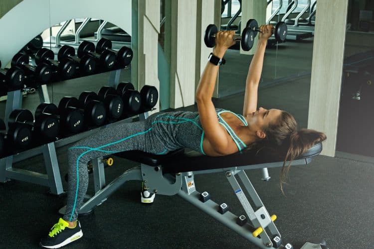 Woman performing bench press during 45-minute upper body workou