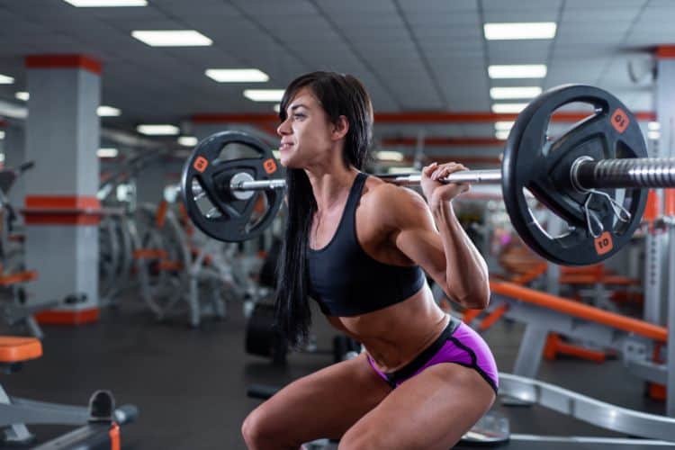 Woman performing barbell back squat in gym – full body compound workout plan