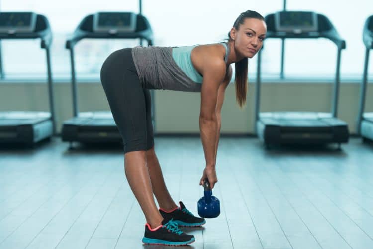 Woman performing kettlebell deadlift in a full body kettlebell complex workout