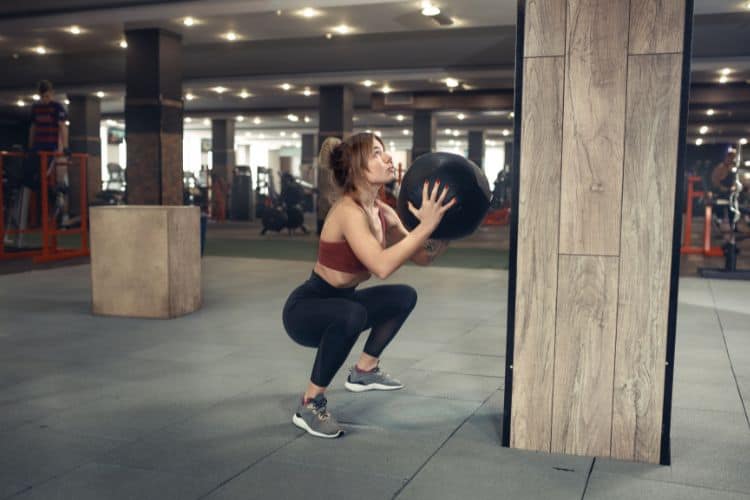 Woman doing squats at home as part of a 30-day full body workout challenge