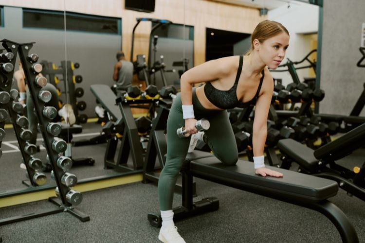 Woman doing bent over rows with light dumbbells weight during 20-minute HIIT workout