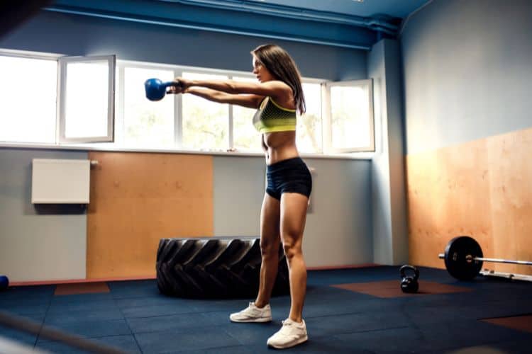 Woman performing kettlebell swing during HIIT workout