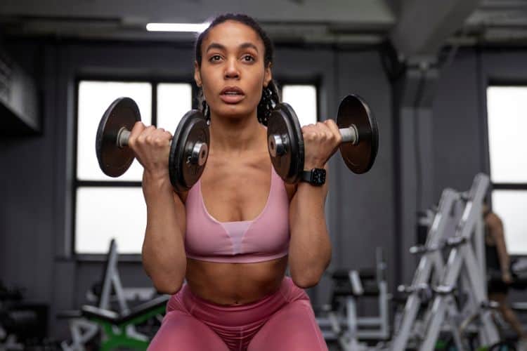 Woman performing dumbbell squat to press during 15 minute HIIT workout with light weights