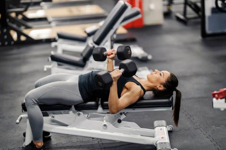 Woman performing bench press with barbell demonstrating progressive overload