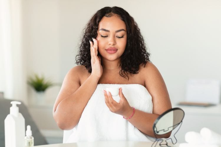 Woman applying serum as part of skincare layer routine