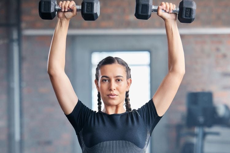 Woman performing dumbbell shoulder press during a 30-minute light weight HIIT workout