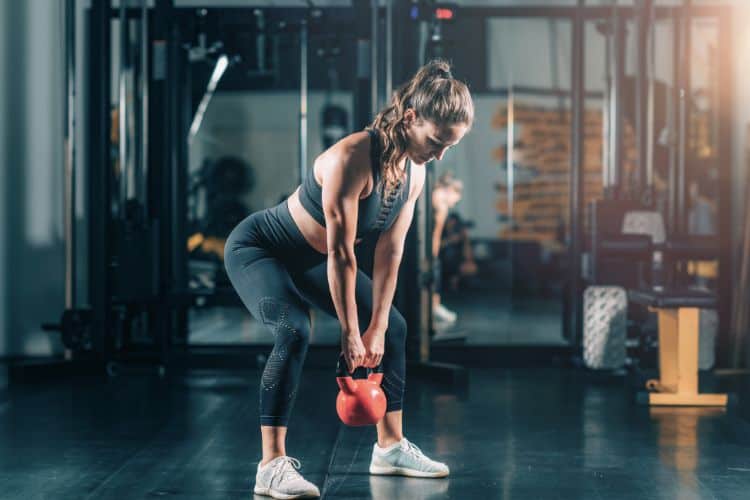 Woman performing explosive kettlebell swing during 30-minute power HIIT workout