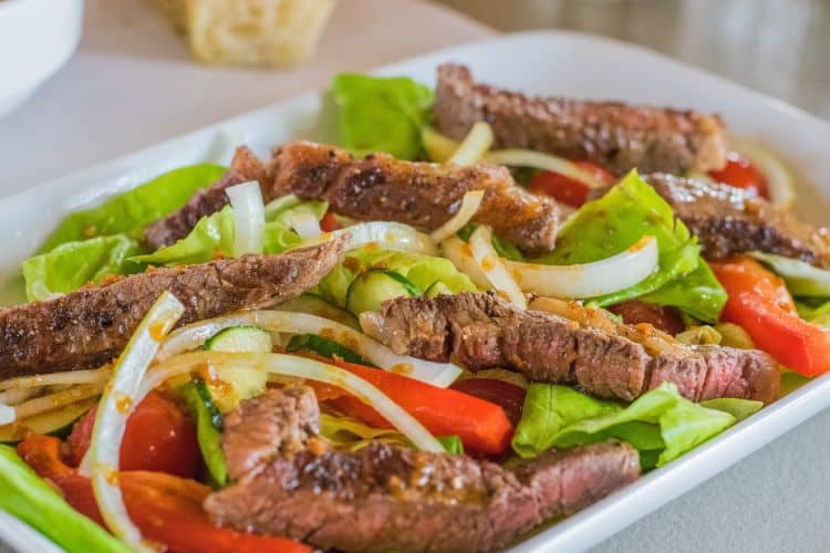 Juicy grilled steak slices on a fresh salad with balsamic vinaigrette