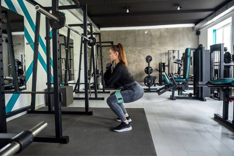 Woman performing a bodyweight squat as part of a 10-minute full body strength training workout routine.