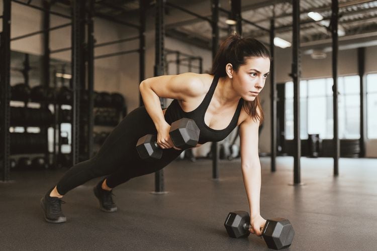 Woman doing a Renegade Rows during a 20 minute hiit dumbbell workout