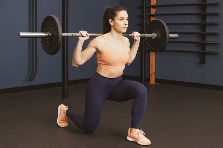 A woman performing Barbell Lunges during a 10-minute full-body workout plan in the gym.