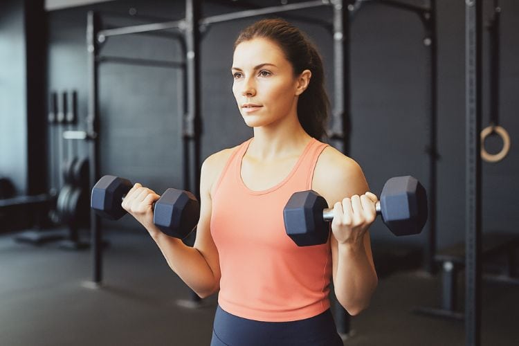Woman performing dumbbell bicep curls during an early 15 minute morning workout.