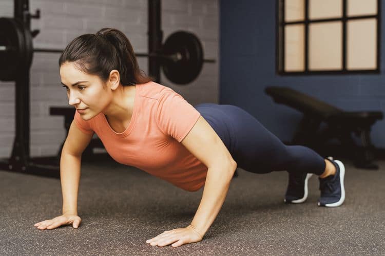 woman performing a 10 minute calisthenics workout in a gym demonstrating a push up workout