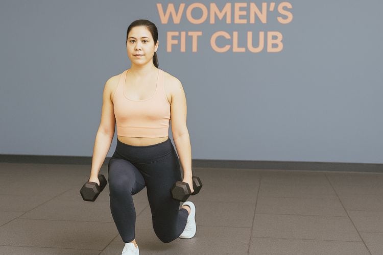 Woman performing dumbbell Reverse Lunge during 45-minute full body dumbbell workout routine in the gym