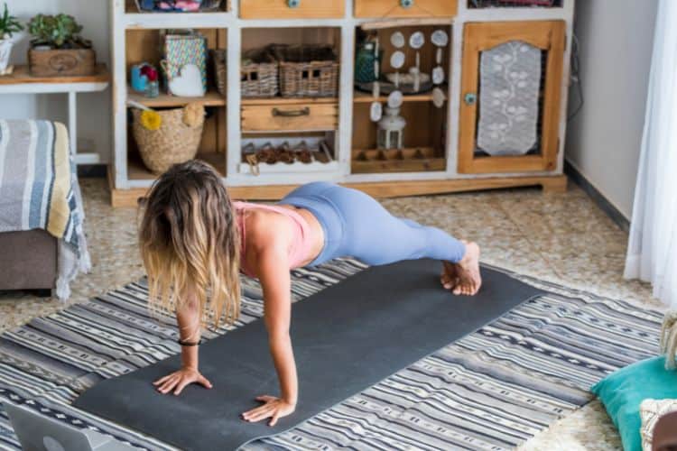 Woman performing a push-up at home on a yoga mat during a 30 minute full body workout.