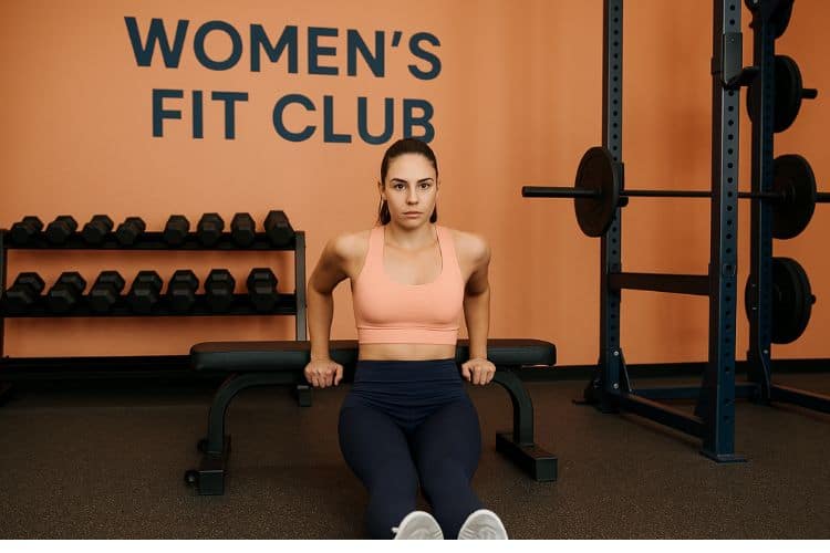woman performing a tricep dips in a gym, demonstrating progressive overload strength training workout plan.