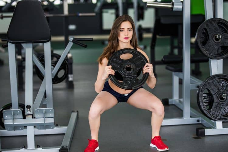 A woman performing a goblet squat with a weight plate during a 30-minute home workout