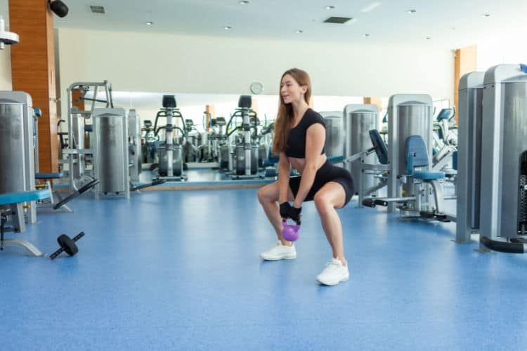 Woman performing a powerful two-handed kettlebell deadlift during a 10-minute full body kettlebell workout.