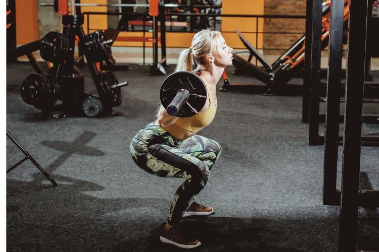 A woman performing a barbell back squat during a 10-minute progressive overload home workout.
