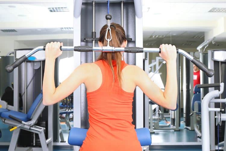 A Woman performing a lat pulldown for a 20 minute back workout in a gym.