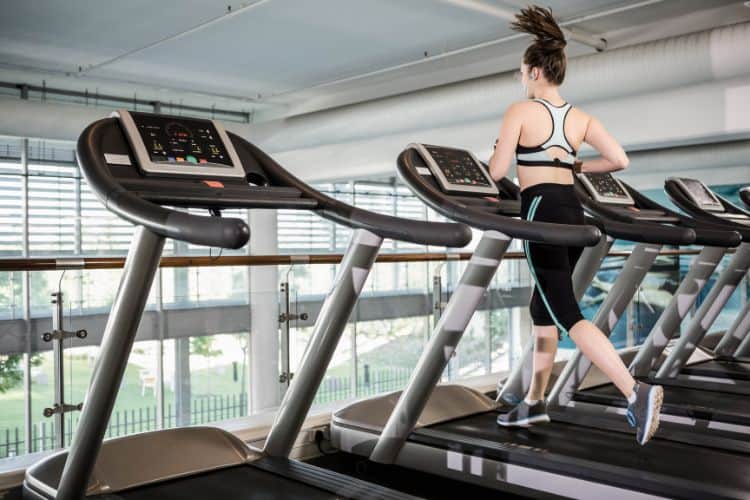 A woman running on a treadmill during a 25-minute workout, looking motivated.