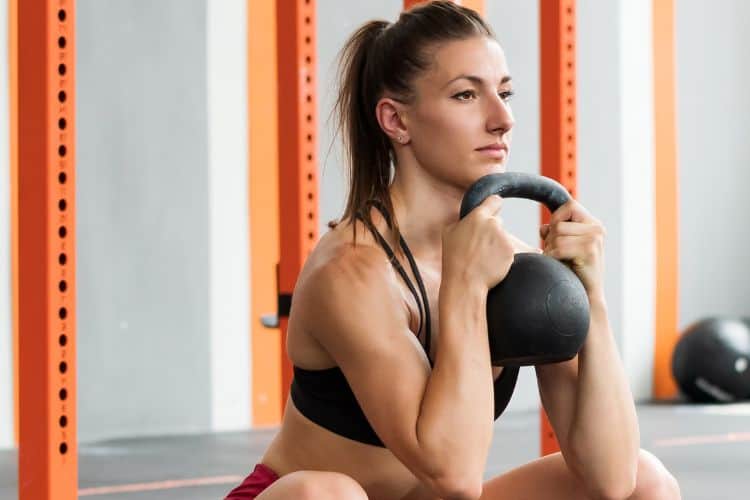 Woman performing a sumo squat during a 30-minute no-repeat HIIT workout in the gym.
