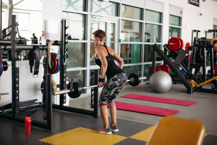 A woman performing a barbell bent over row during a 45-minute progressive overload workout.