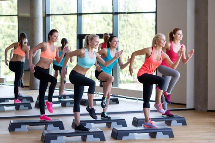 women performing a high-energy 5-minute fat burning cardio exercise routine in a gym room.
