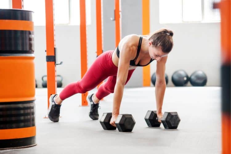 Woman performing push ups in a 5 minute HIIT arm workout in the gym.