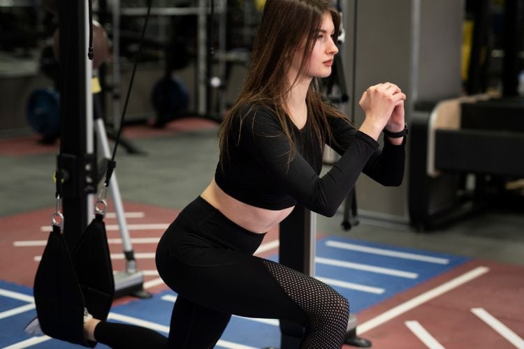 Woman performing bulgarian split squats during a 30-minute full body calisthenics workout plan in the gym.