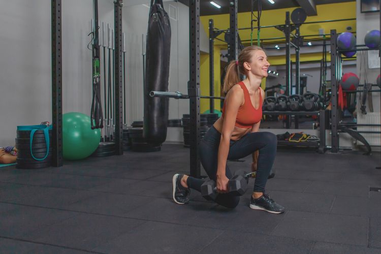 Woman performing a reverse lunges in a 20-minute full body strength and cardio workout in a gym.
