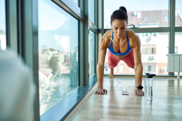 A woman performing a push-up in a 30-minute full body MetCon HIIT workout.