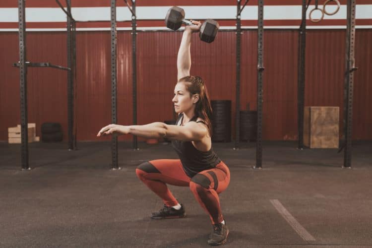 A woman performing dumbbell squat to press during a 45-minute dumbbell strength training workout.
