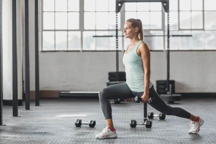 Woman doing reverse lunges during a 15-minute workout plan in a gym.
