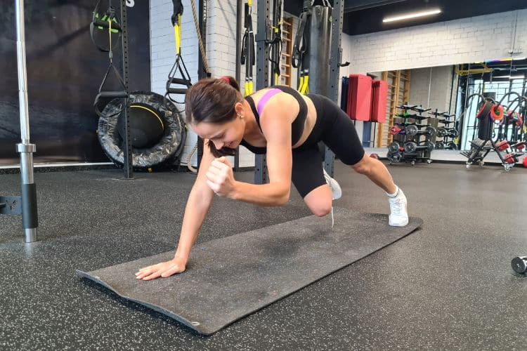 Woman performing a high-intensity interval Mountain Climbers workout in a gym, demonstrating a 25-minute full body workout fitness plan.