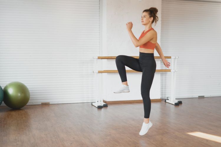 Woman performing a high-knee run as part of a quick 5-minute HIIT workout at a gym.