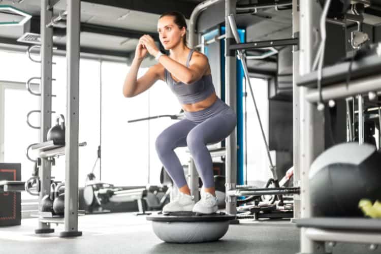 Woman demonstrating proper form for beginner bodyweight squats, part of the 10 minute beginner full body workout.