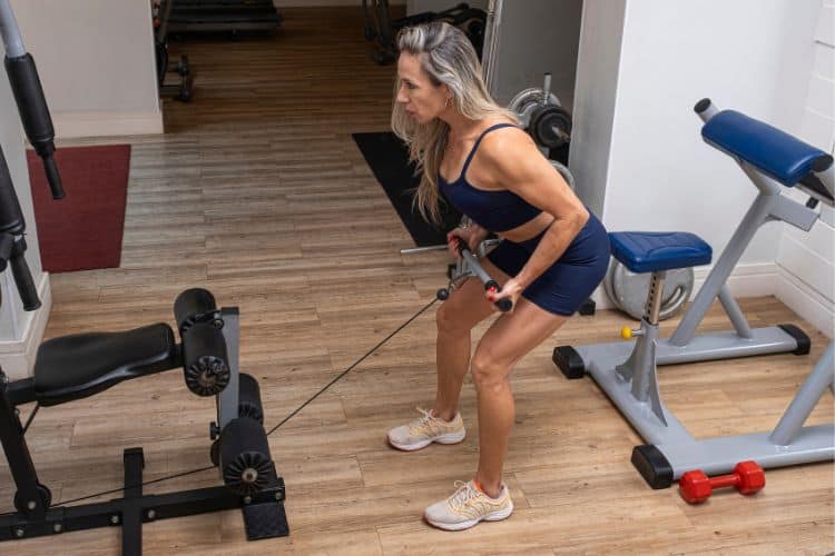 Woman isolating her bicep with arm cable curl, focusing on muscle mind-connection during 30 minute cable machine arm workout.