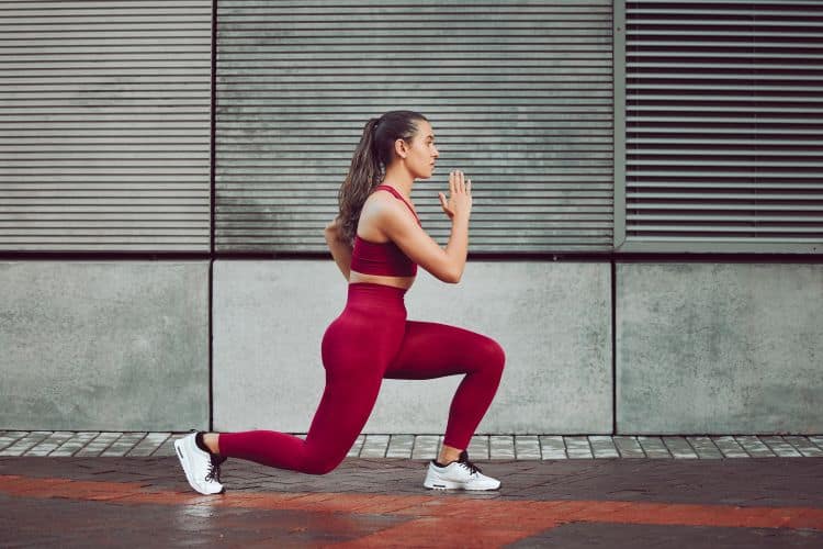 Woman performing a bodyweight reverse lunges in the gym during a 30-minute beginner bodyweight workout.