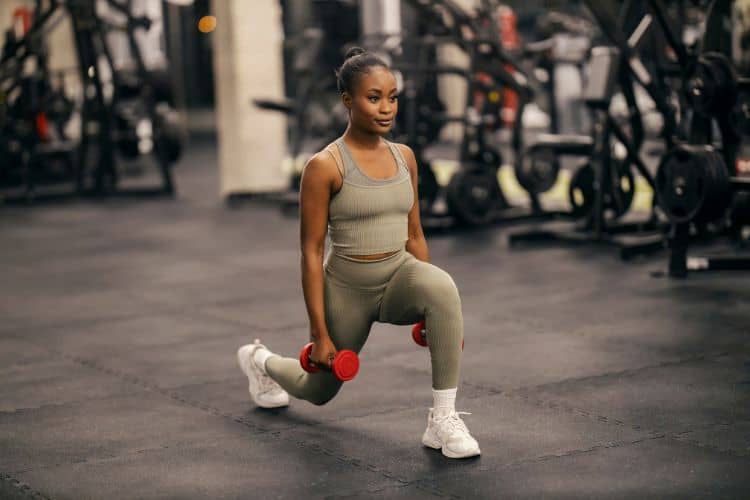 A woman performing dumbbell reverse lunges during a 45-minute full body workout with dumbbells.